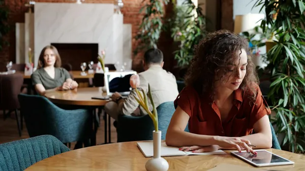 Clienta consultant la carta d'un restaurant des d'una tauleta en una terrassa moderna