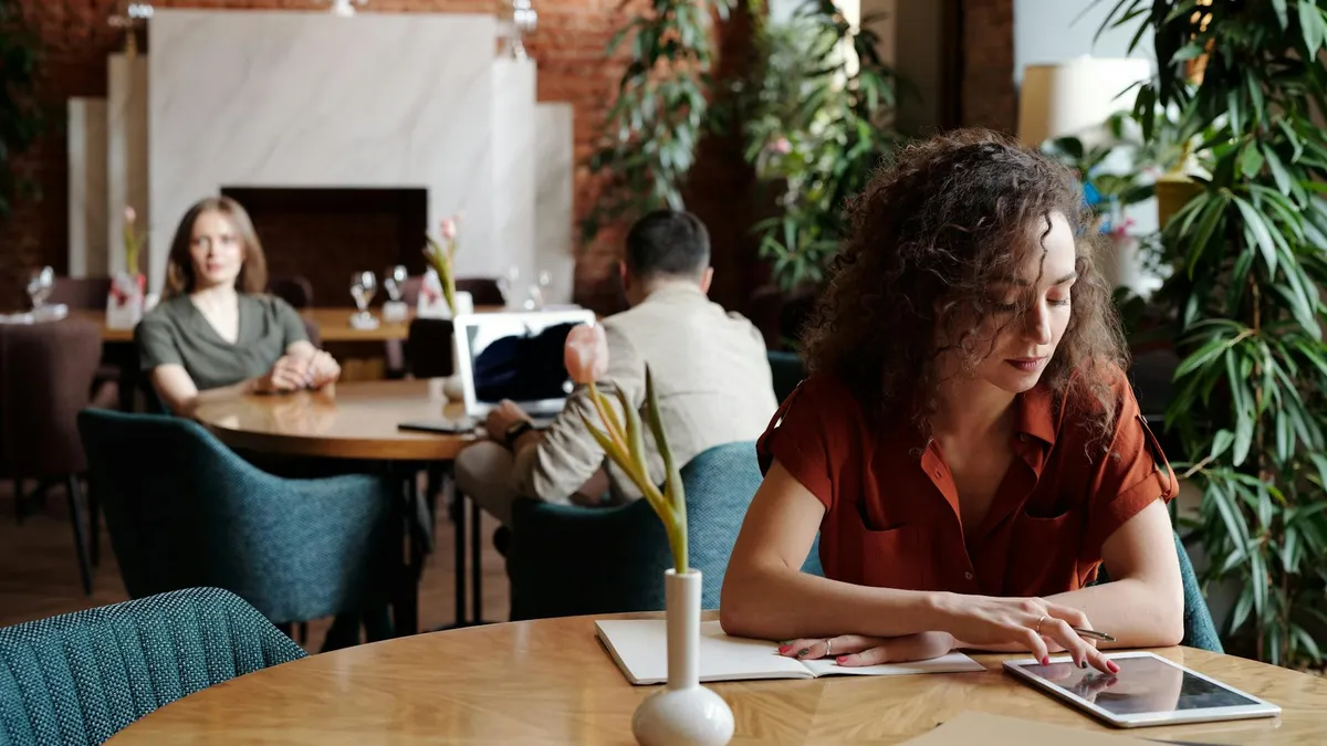 Clienta consultant la carta d'un restaurant des d'una tauleta en una terrassa moderna
